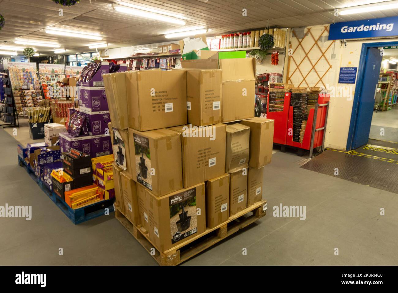 A pallet of brown boxes on a shop floor with items waiting to be put on