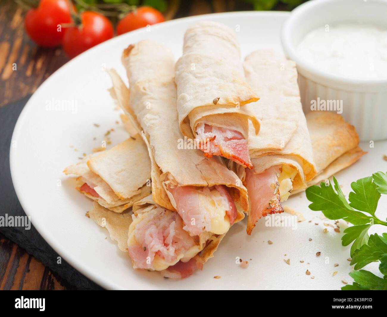 tasty pita bread rolls with cheese and bacon and white sauce. Selected focus. Stock Photo