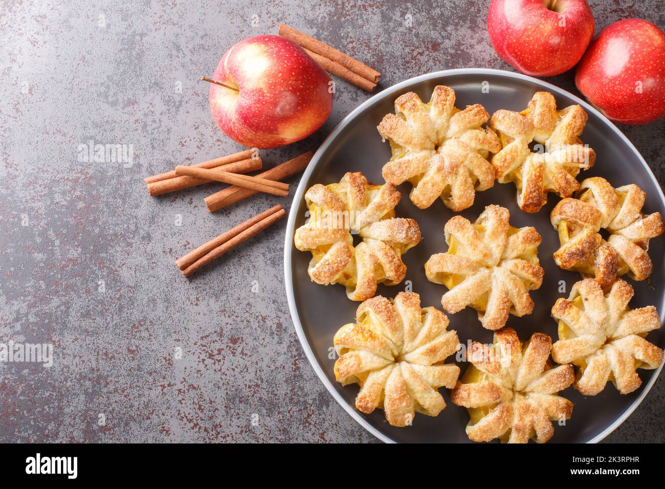 Autumn dessert Apple puff pastry with sugar and cinnamon close-up in a plate on the table. Horizontal top view from above Stock Photo