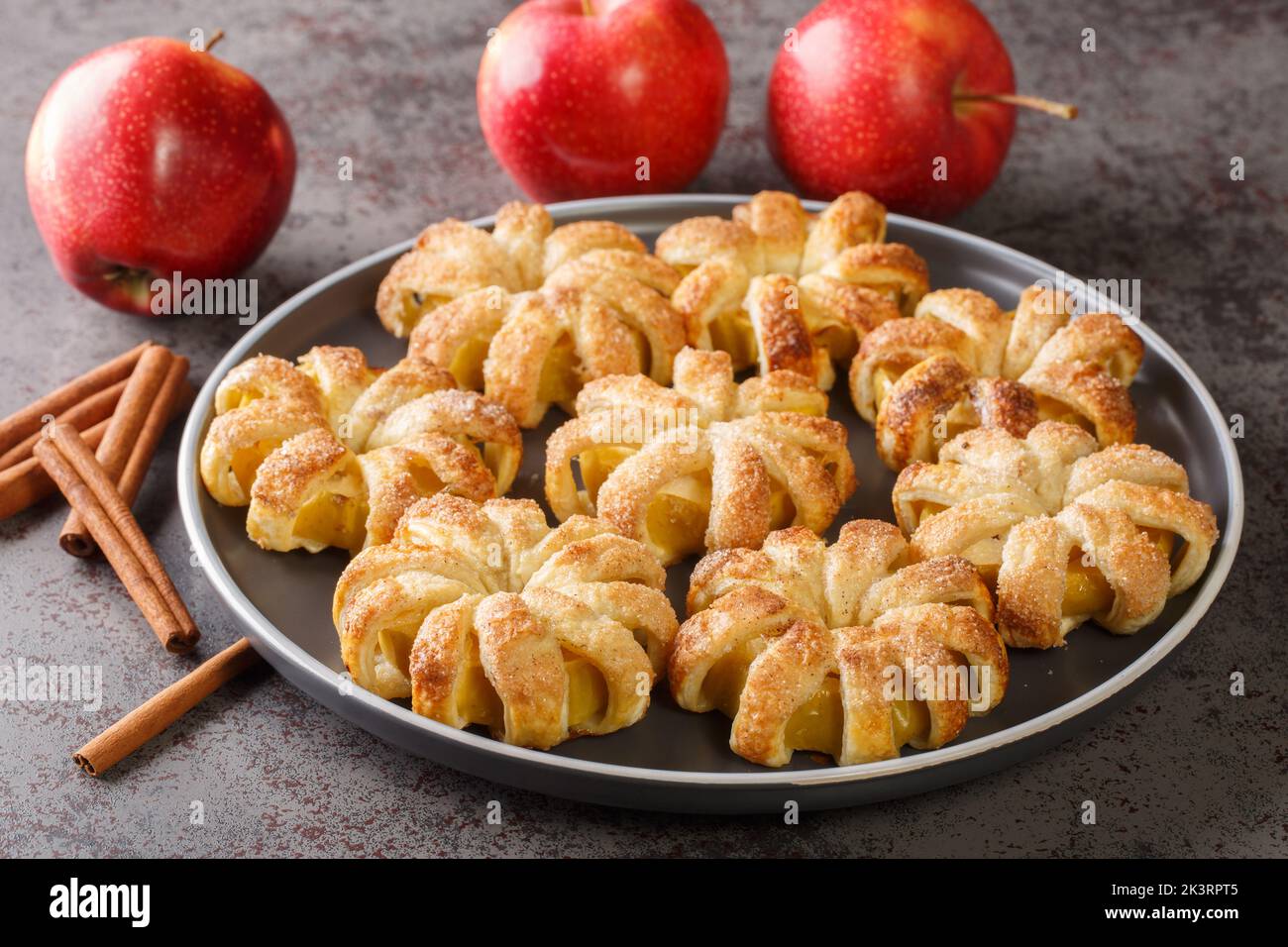 baked apples wrapped in puff pastry and sprinkled with sugar and cinnamon close-up in a plate on the table. horizontal Stock Photo
