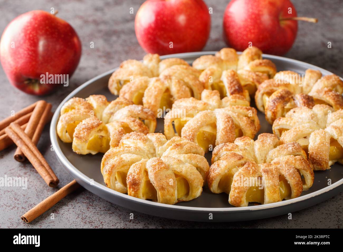 Autumn dessert Apple puff pastry with sugar and cinnamon close-up in a plate on the table. Horizontal Stock Photo
