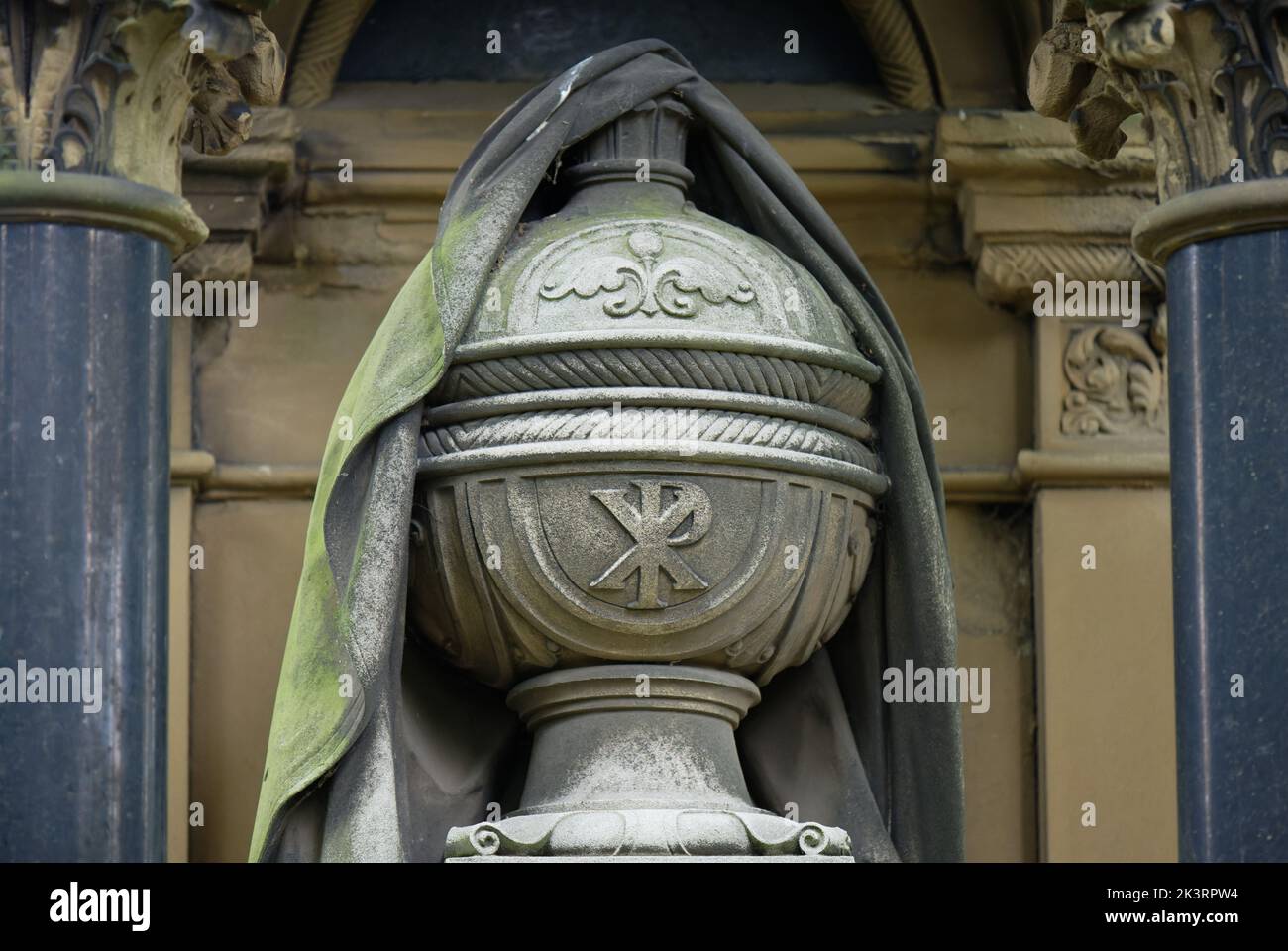 antique funeral urn with burial shroud and inscription Chi Rho in a cemetery Stock Photo