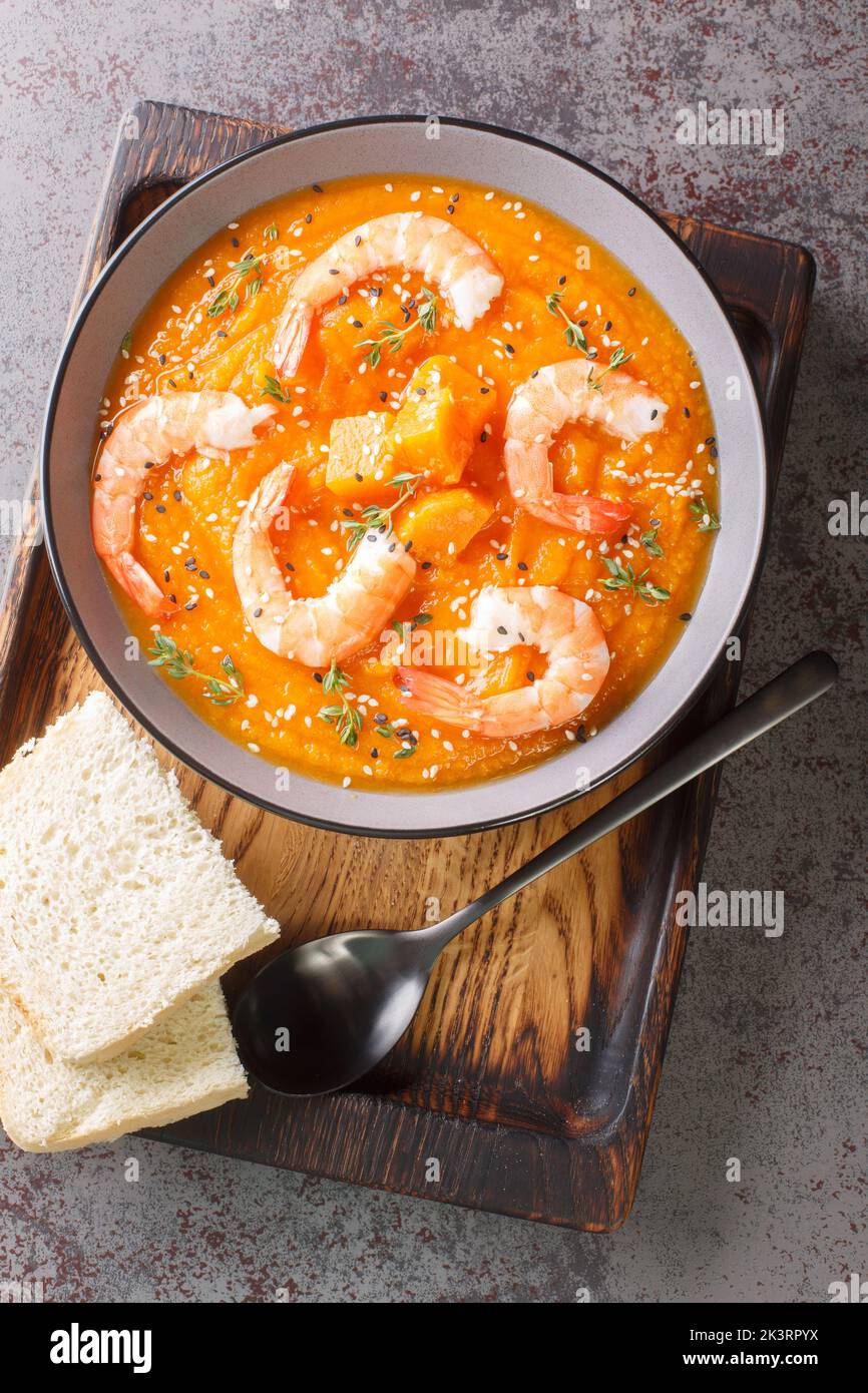 spicy pumpkin and shrimp soup with sesame and thyme closeup in the bowl on the table. Vertical top view from above Stock Photo