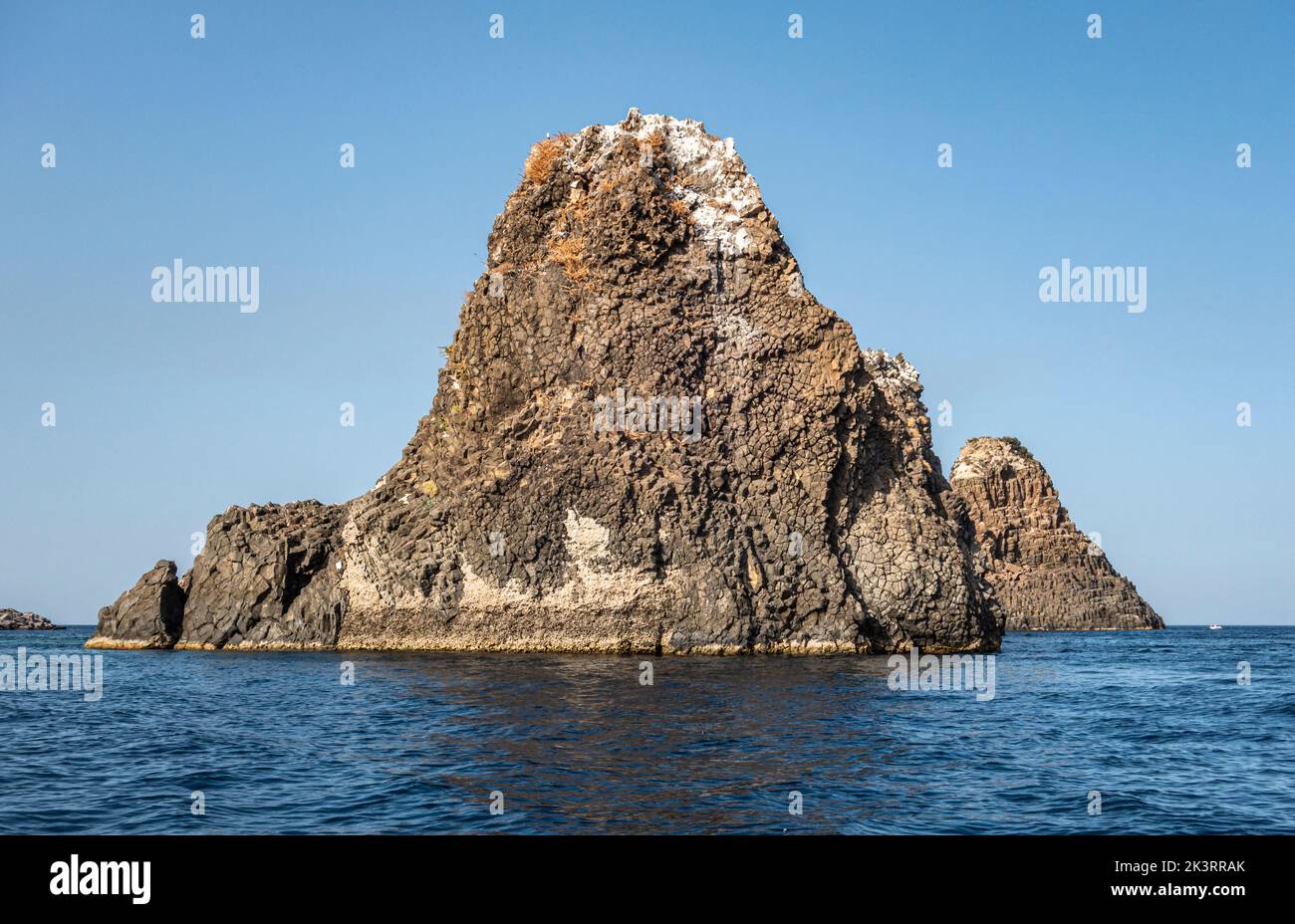 The Faraglioni or Isole dei Ciclopi (Cyclopean Islands), a group of volcanic basalt sea stacks just off the coast at Aci Trezza, Sicily, Italy Stock Photo