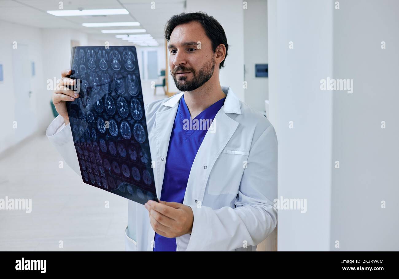 Diagnostics of brain diseases, headaches, tumors and brain cancer with MRI or CT scan. Experienced doctor neurologist looking at MRI scan of patient's Stock Photo