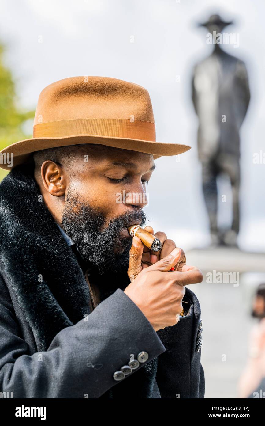London, UK. 28th Sep, 2022. Antelope by Samson Kambalu (pictured discussing his work cigar in hand) on the Fourth Plinth in Trafalgar Square. The sculpture restages a 1914 photograph of John Chilembwe, a Baptist preacher and pan-Africanist, and John Chorley, a European missionary. Chilembwe is wearing a hat in defiance of a colonial rule forbidding Africans from wearing hats in front of white people. He later led an uprising against colonial rule during which he was killed and his church was destroyed by the colonial police. Credit: Guy Bell/Alamy Live News Stock Photo