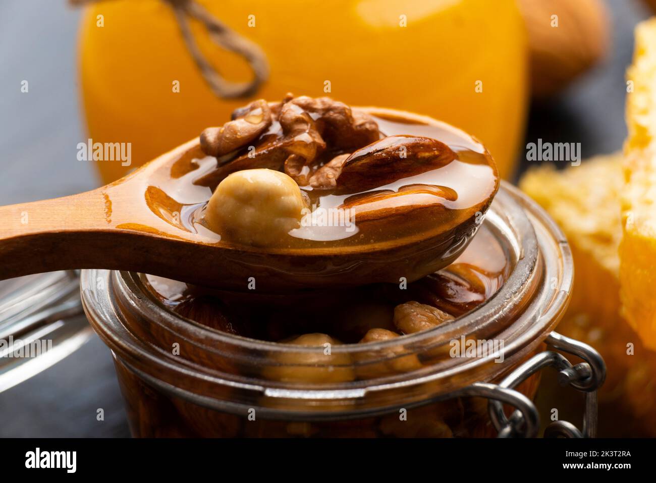 Honeyed assorted nuts in wooden spoon over mason jar organic food background Stock Photo