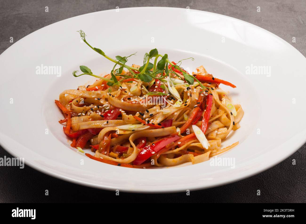 tasty udon wheat noodles with vegetables sesame seeds and microgreens