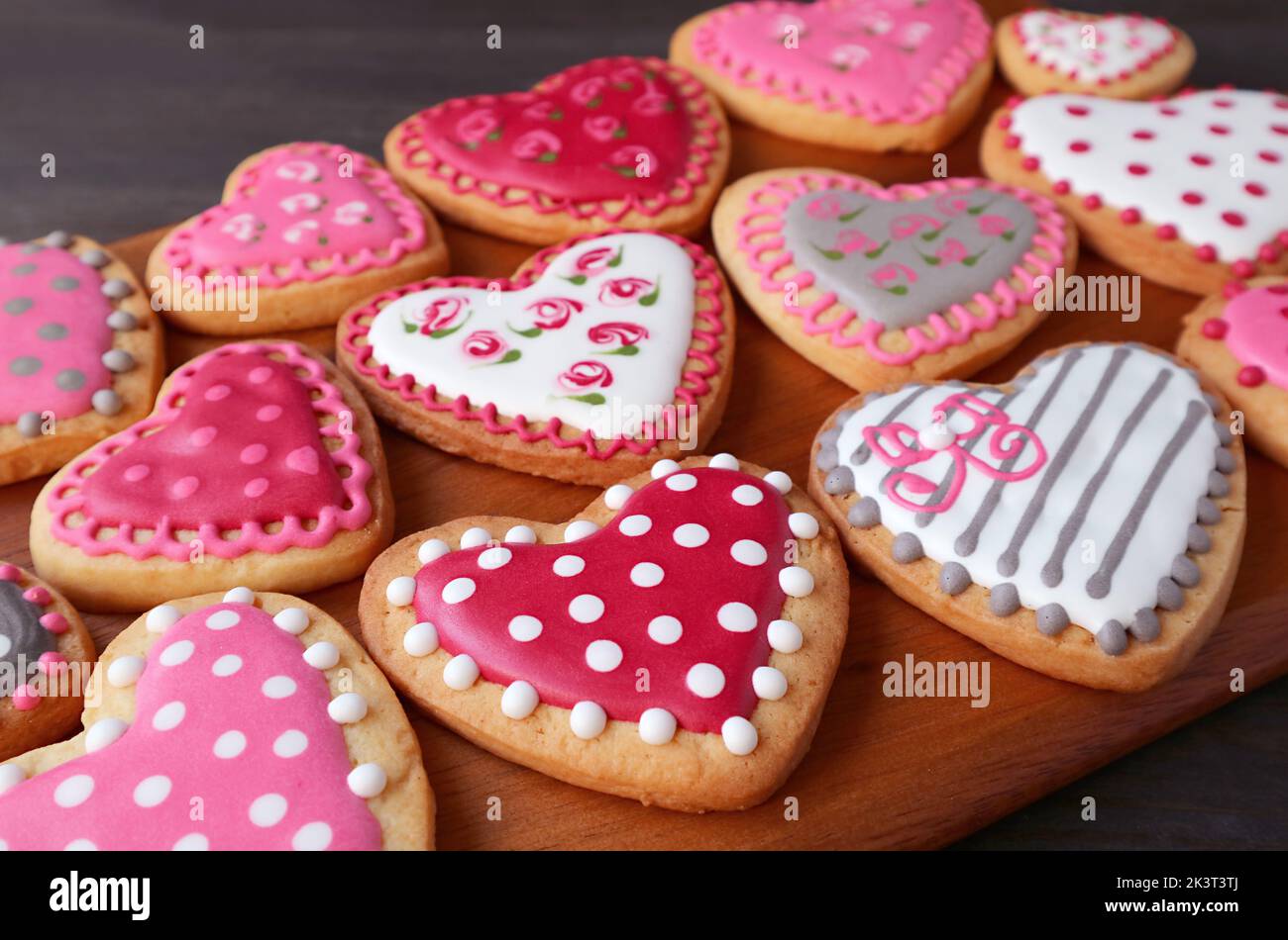 Rows of gorgeous heart shaped with beautiful pattern cookies on wooden breadboard Stock Photo