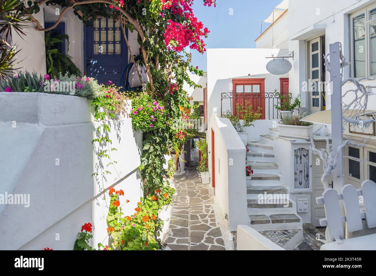 Naxos island, Greece. Traditional Cyclades architecture whitewashed buildings, plants and flowers, souvenir shop, paved alley. Summer holiday destinat Stock Photo