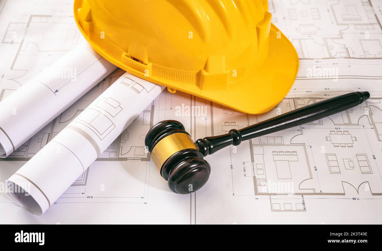 Labor, Construction law. Yellow safety helmet and judge gavel on building blueprint plans, above view. Stock Photo