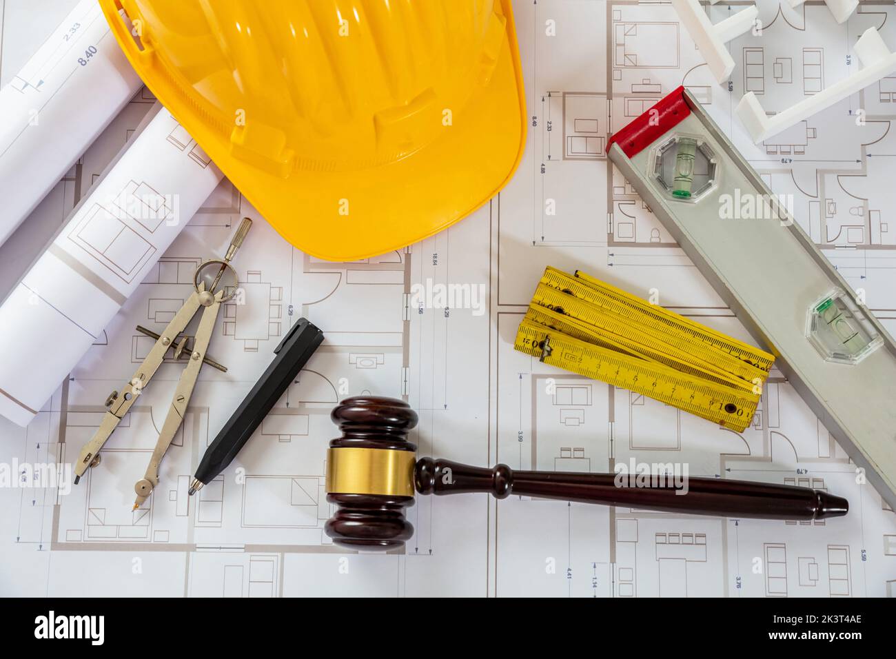 Construction and Labor law flat lay. Yellow safety helmet and judge gavel on building blueprint plans, top view. Stock Photo