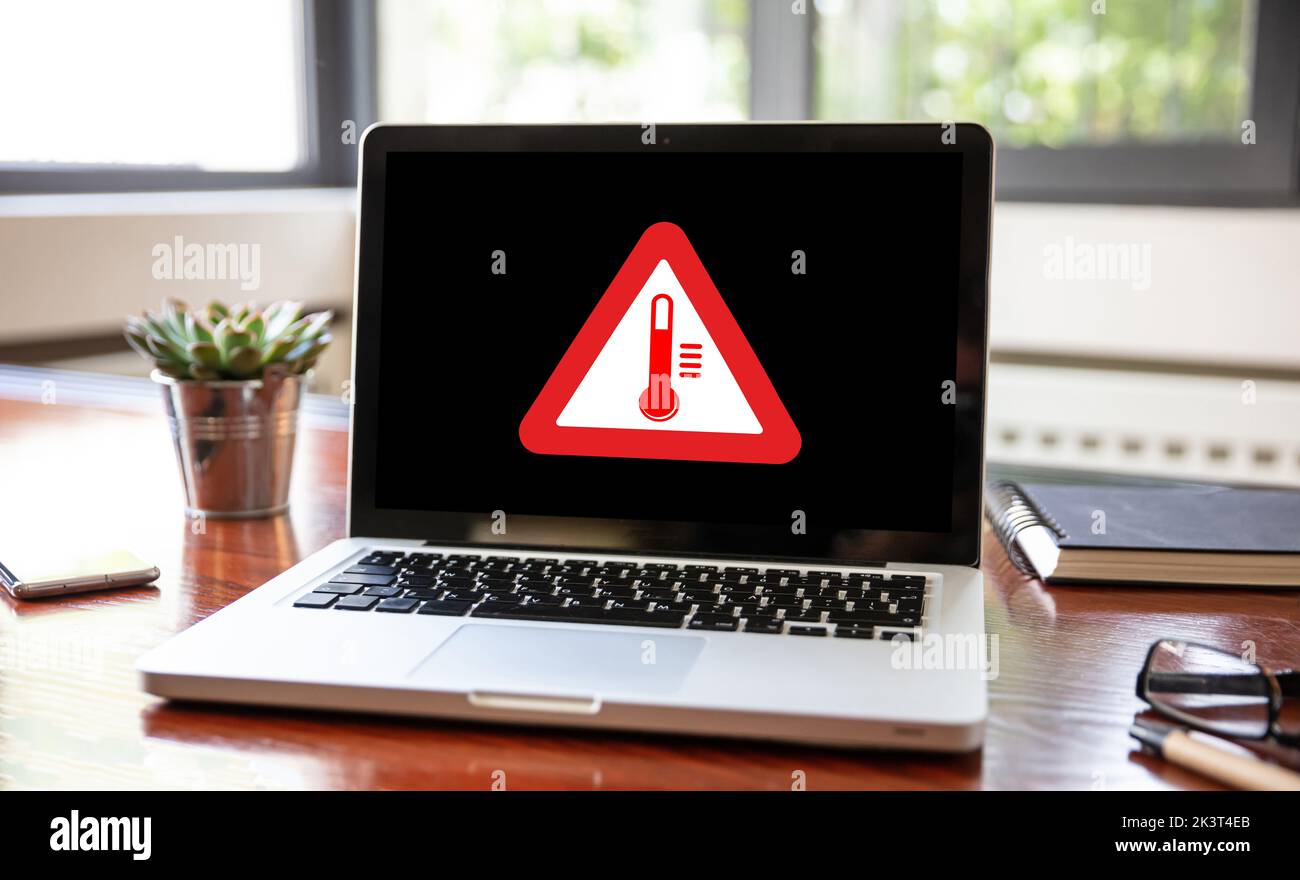 High temperature warning sign on a laptop screen.  Computer overheating concept. Heavy load and hot weather danger. Business office desk background. Stock Photo