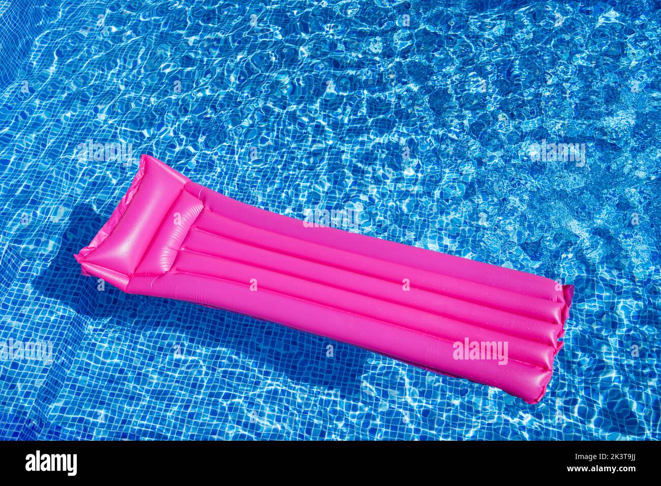 From above of pink inflatable mattress floating on transparent clear