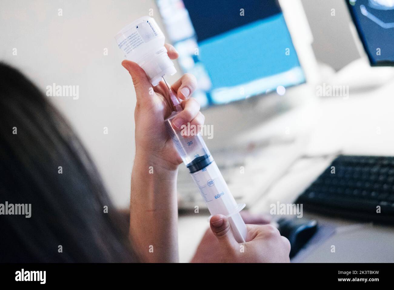 Back view of anonymous female doctor filling in syringe with medicine ...