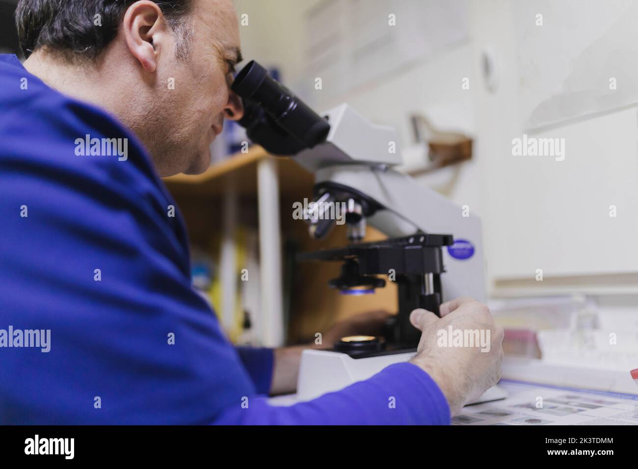 Doctor looking through microscope in hi-res stock photography and ...