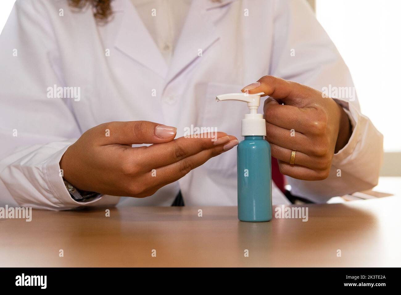 Crop anonymous female in medical uniform with bottle of antibacterial ...