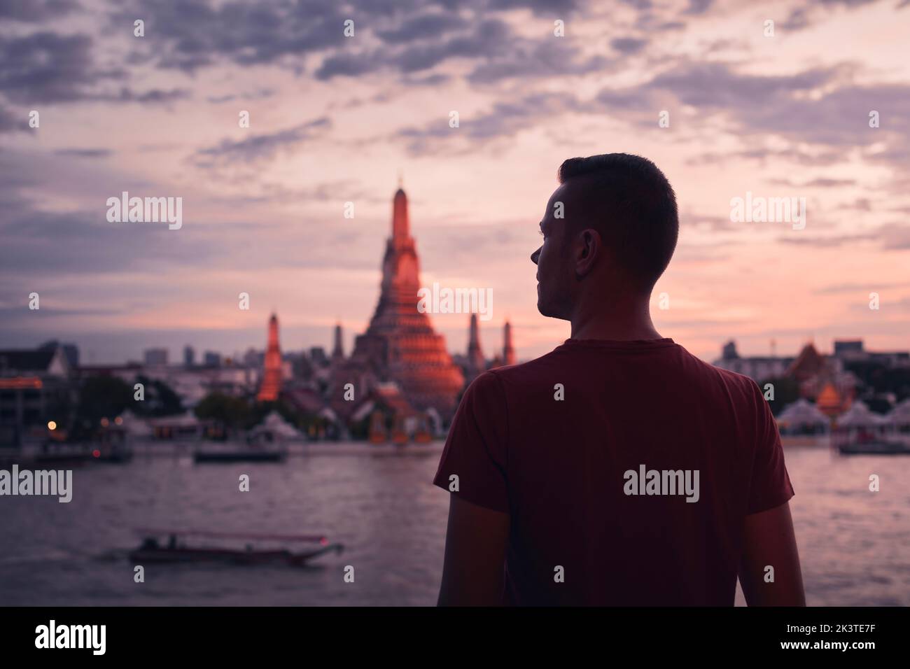 Rear view of tourist against cityscape with Chao Phraya River and Wat Arun at beautiful sunset. Bangkok, Thailand Stock Photo
