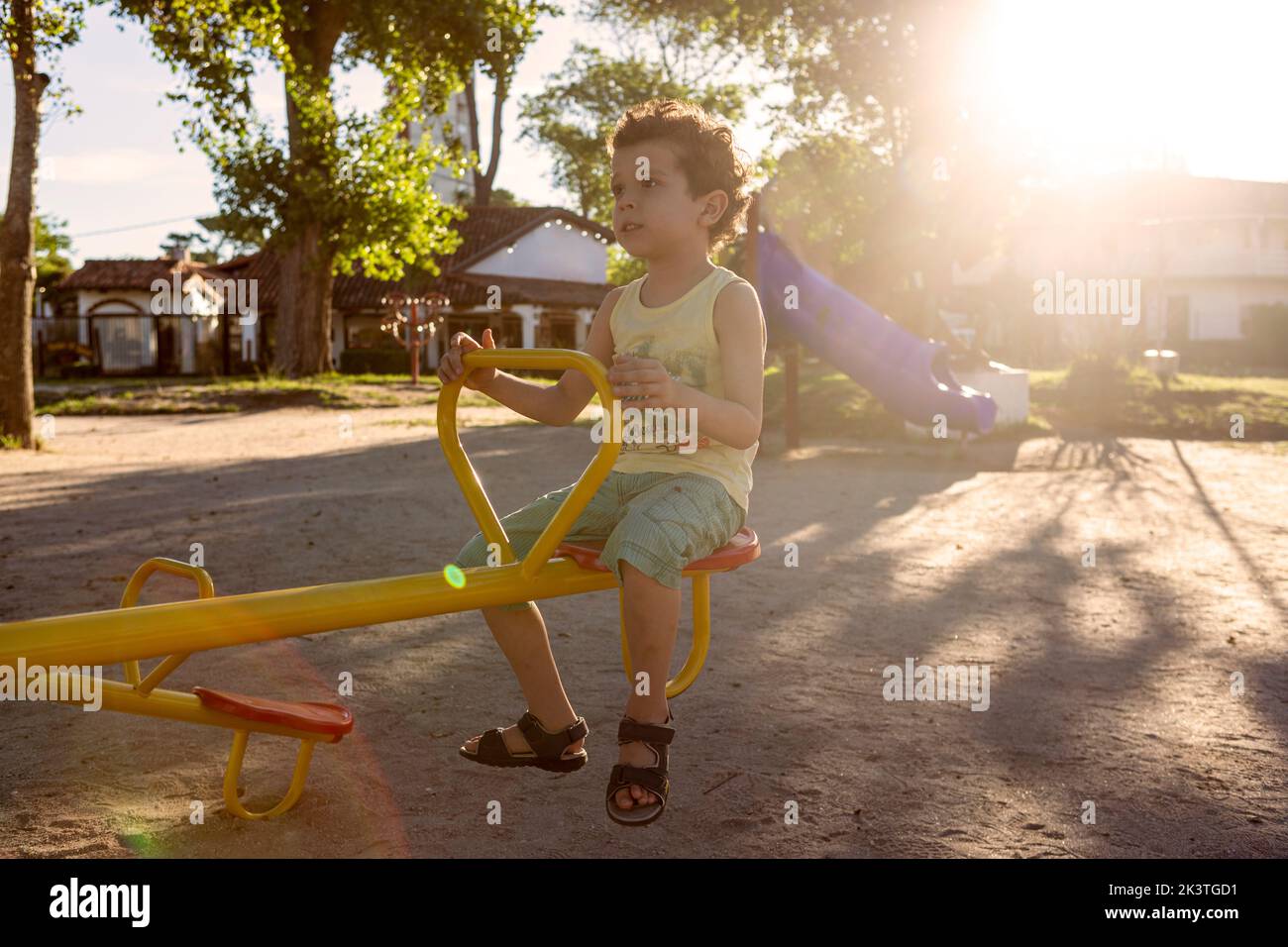 little boy of Caucasian appearance with curly hair riding on a seesaw in the park Stock Photo
