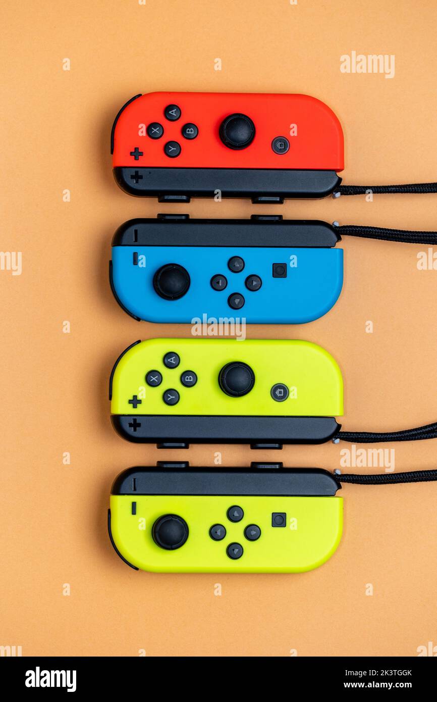 Nintendo Switch Joy-Cons aligned in a row. Yellow blue and red Joy-Cons top view with orange Background. Stock Photo