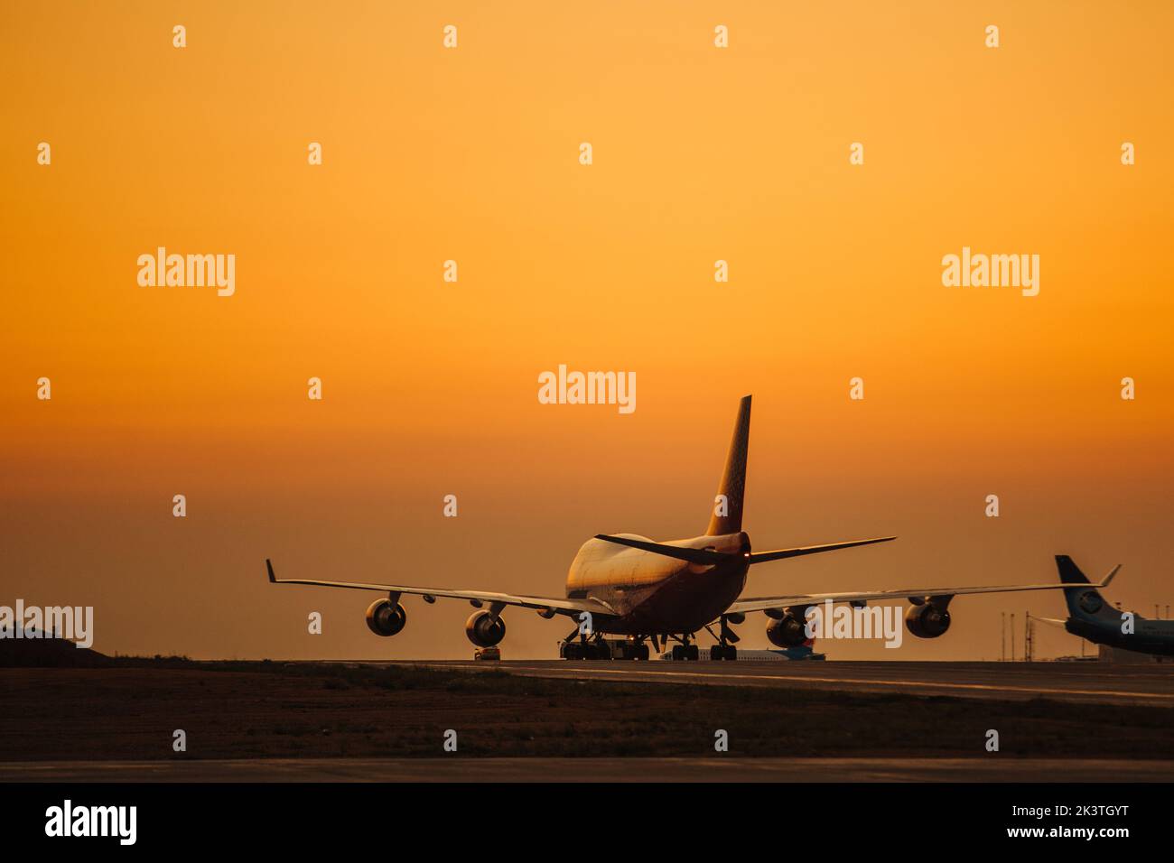 Passenger airplane take off from airport runway against the backdrop of a picturesque evening sky with sun rays. Stock Photo