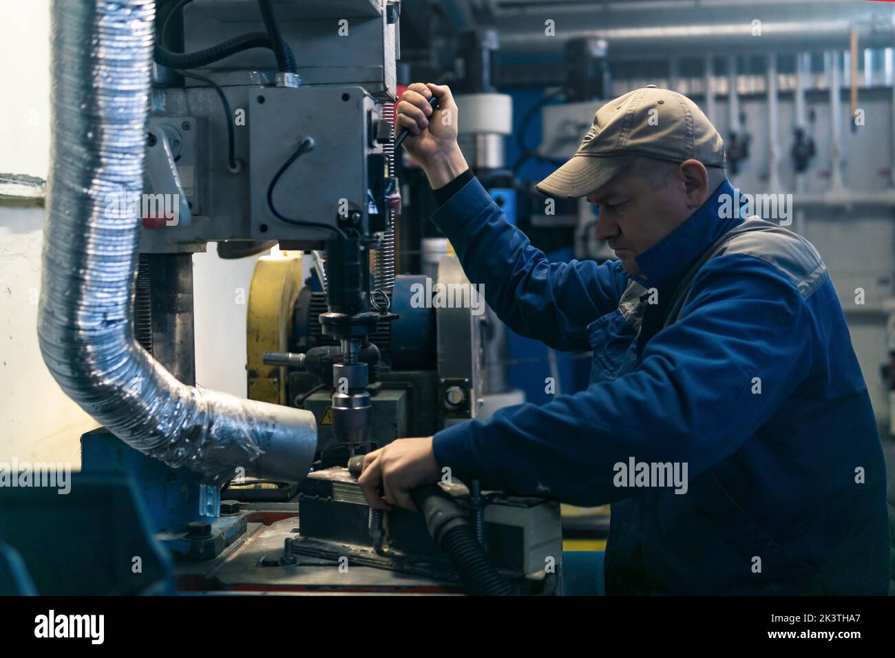 Perm, Russia - September 21, 2022: worker in a semi-dark workshop works on a drilling machine Stock Photo