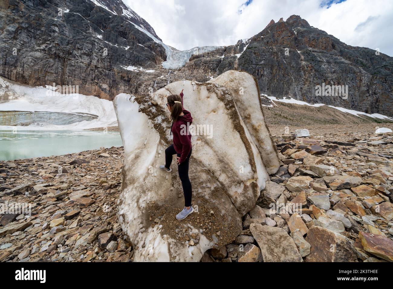 Woman poses with a large iceberg chunk at Mt. Edith Cavell and Angel Glacier Stock Photo