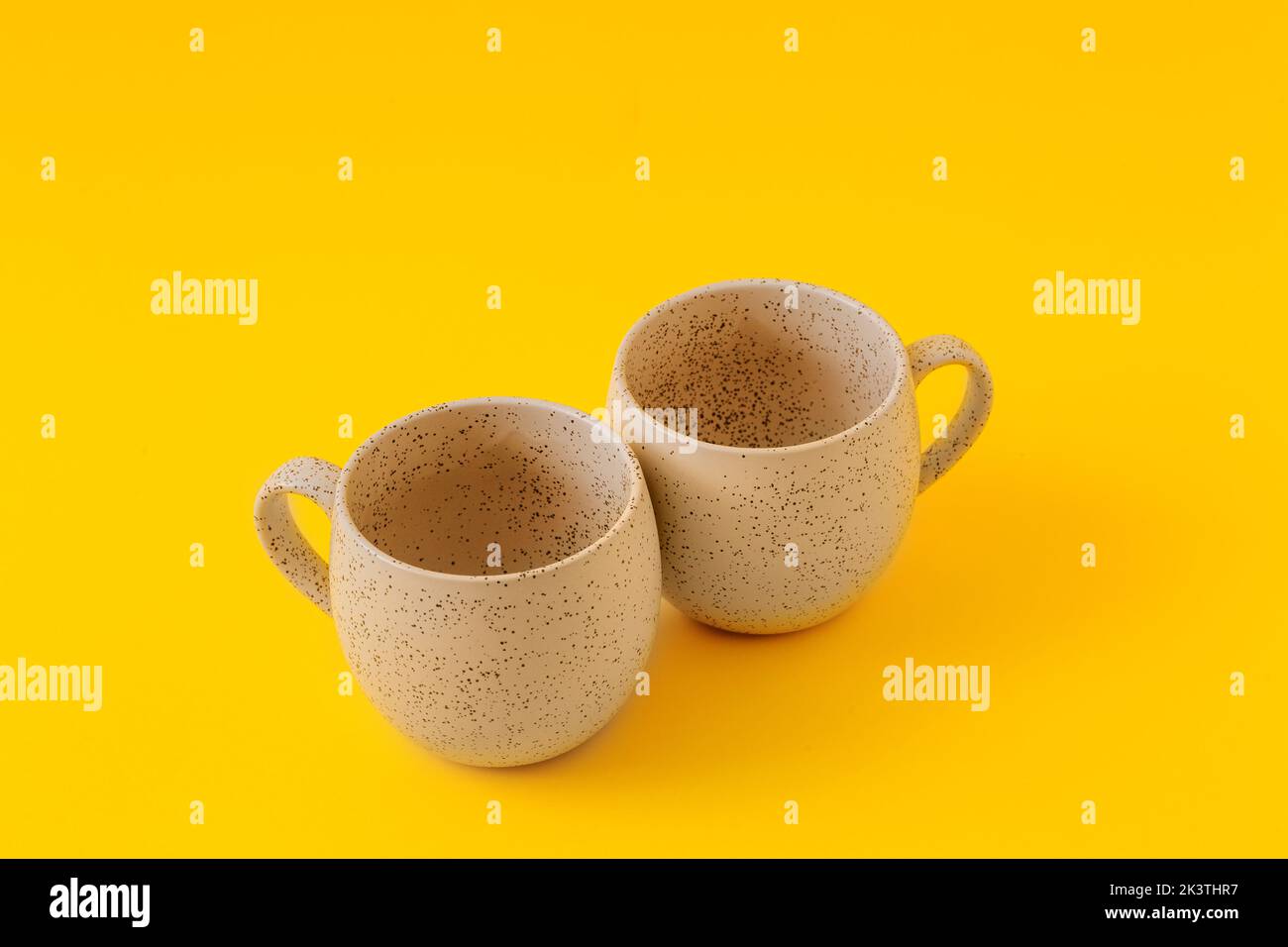Two empty ceramic cups on a yellow background, copy space. Stock Photo