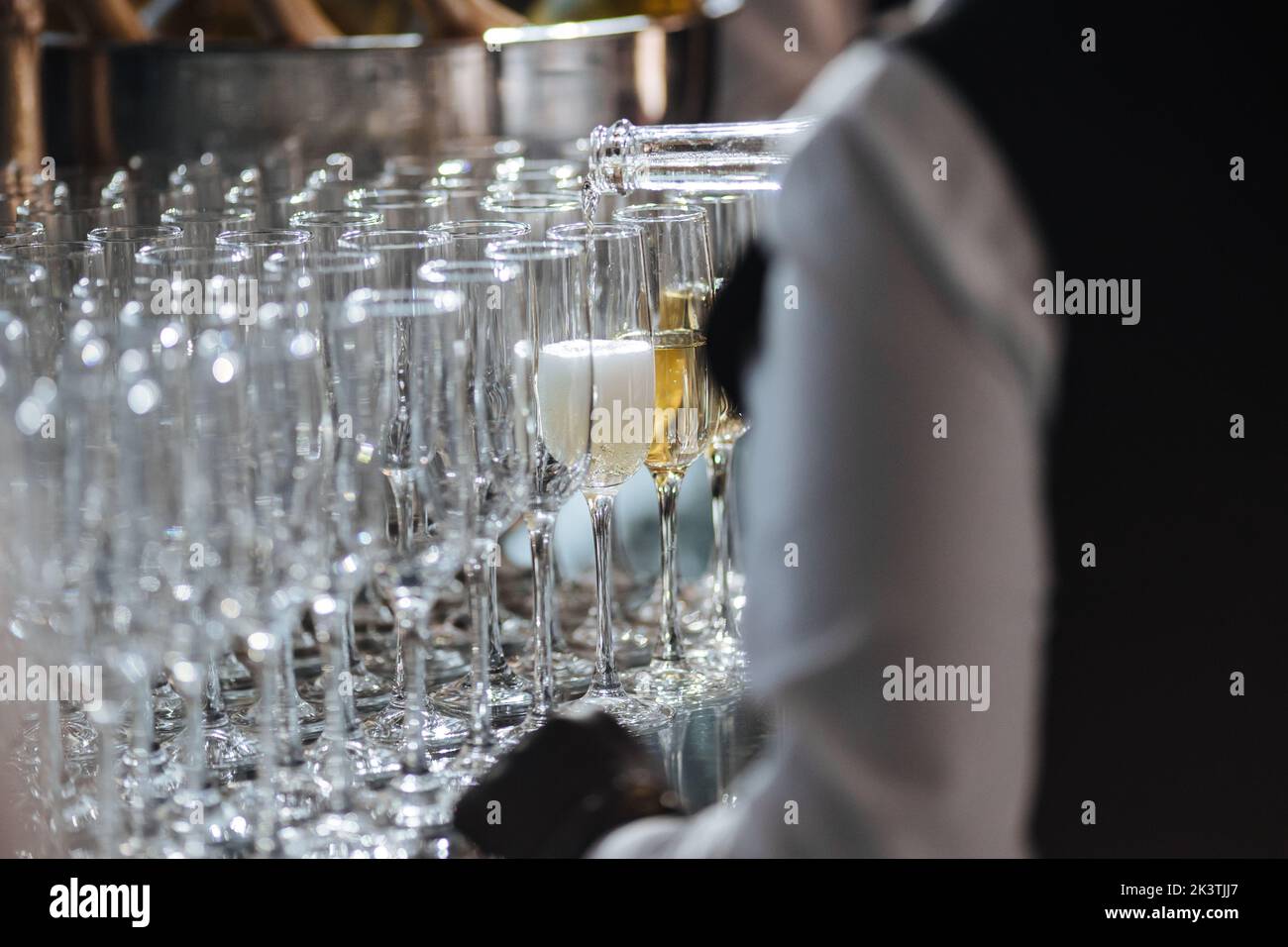 Waiter pouring champagne in stylish glasses at luxury reception, celebration. expensive catering and service at feast. new year and christmas celebrations and drinks, holiday Stock Photo
