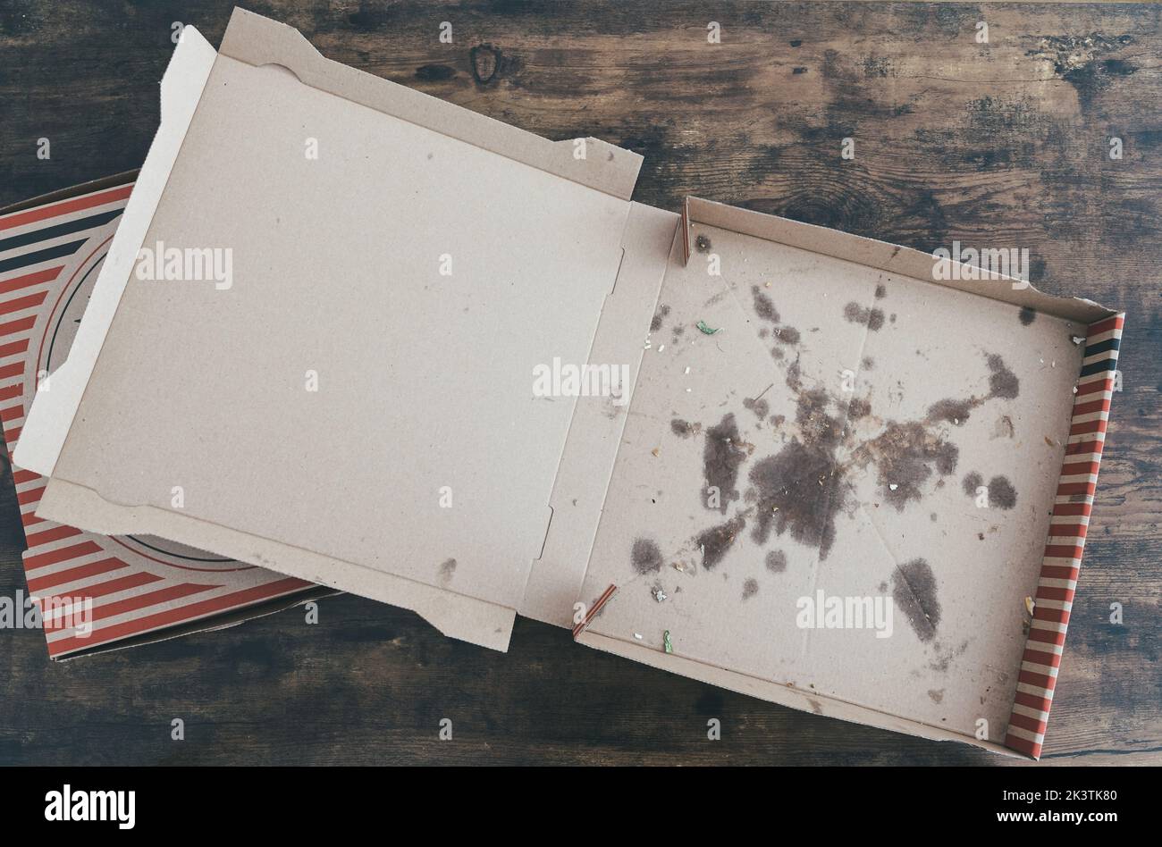 top down view of empty stained cardboard pizza delivery boxes on rustic wooden table Stock Photo