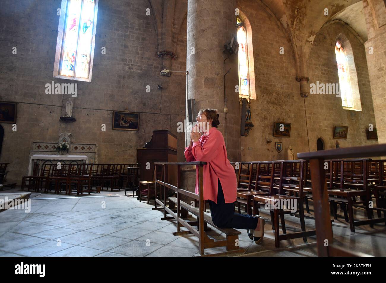 Christian woman praying in Church of Sainte-Marie in Montreal in the Lot-et-Garonne department, Southwestern France. Montréal-du-Gers. Church of Sainte-Marie. The church is on the Camino De Santiago route for pilgrims. Stock Photo