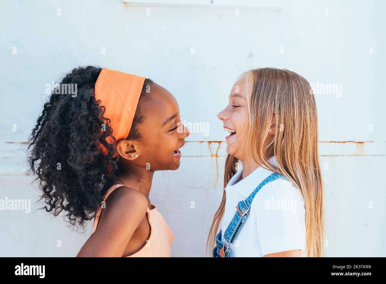 Cheerful African American girl with best friend having fun near white wall Stock Photo