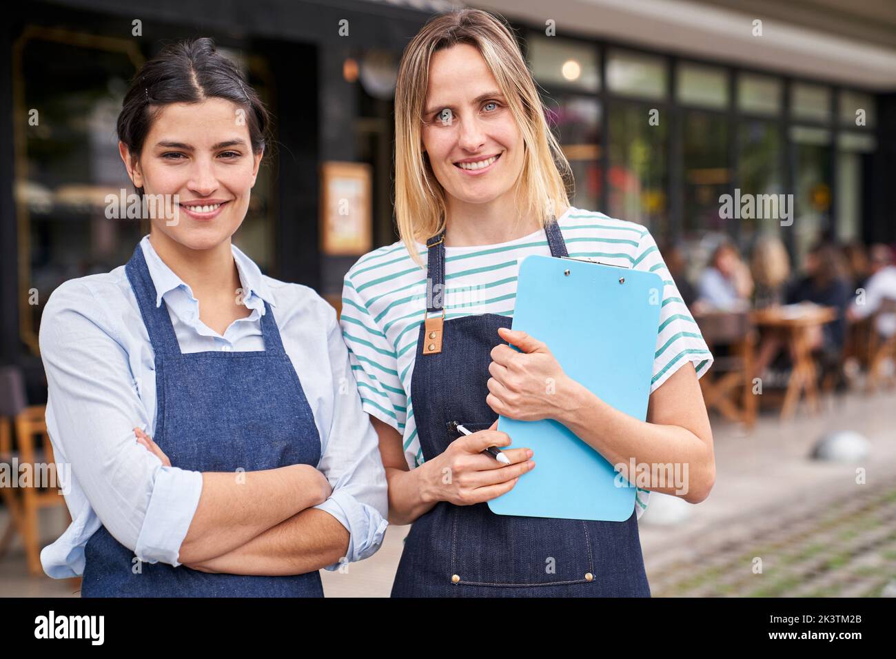 Medium shot of two female restaurant owners looking at camera while standing outside their restaurant Stock Photo