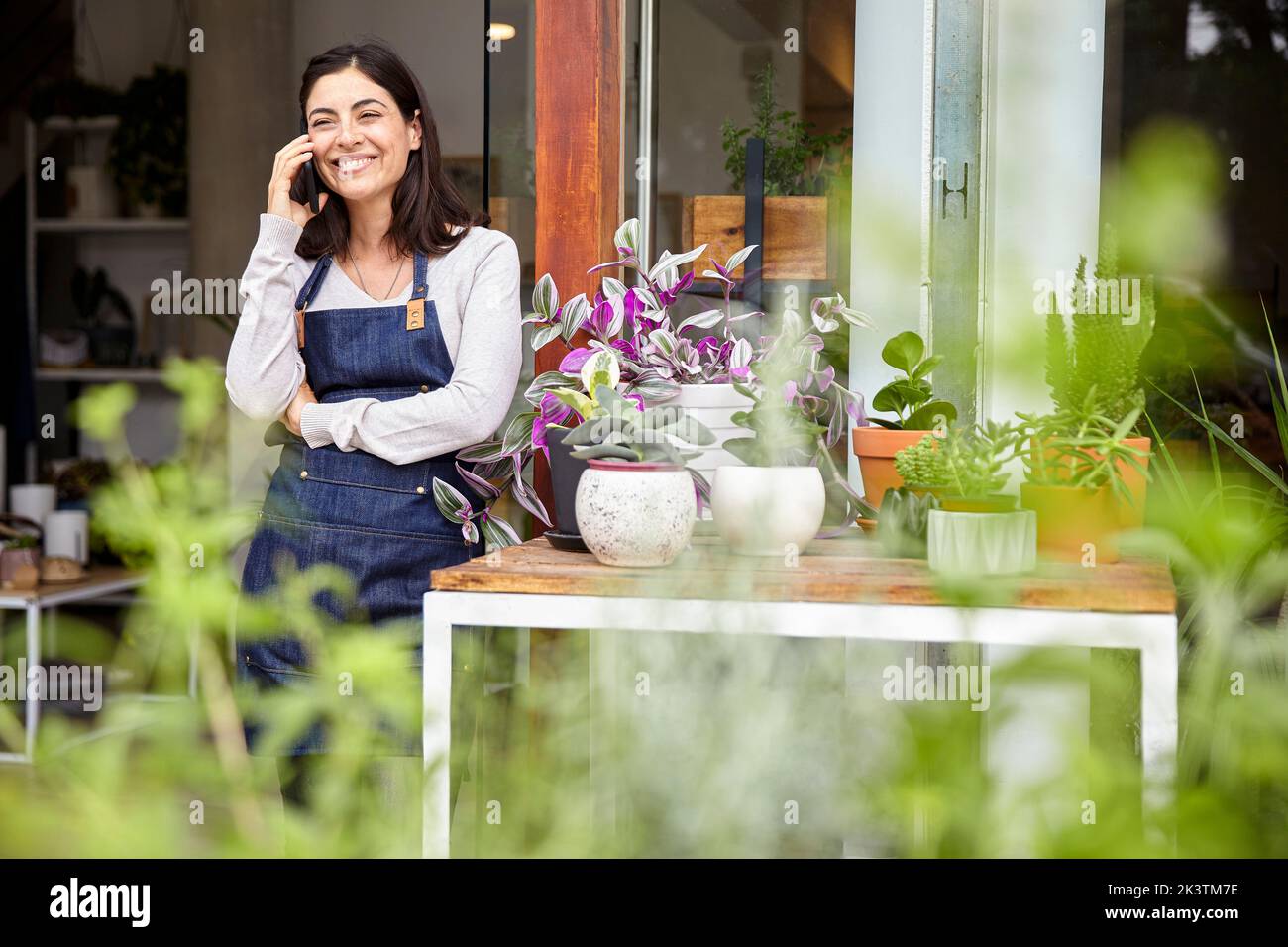 Cheerful young adult female entrepreneur talking on smartphone Stock Photo