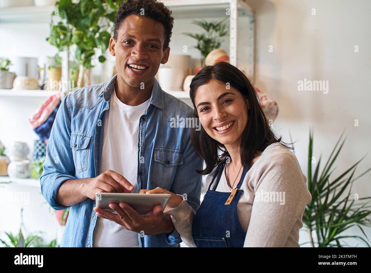 Plant nursery owners smiling at the camera while using digital tablet Stock Photo