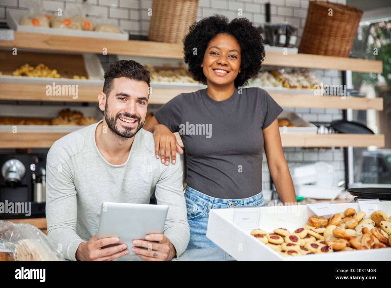 Bakery owners standing behind counter while holding digital tablet Stock Photo