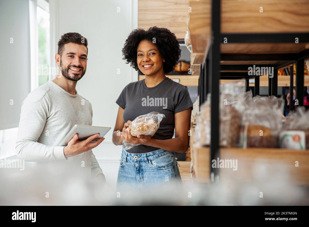 Male and female entrepreneur looking at the camera while standing in pastry store Stock Photo