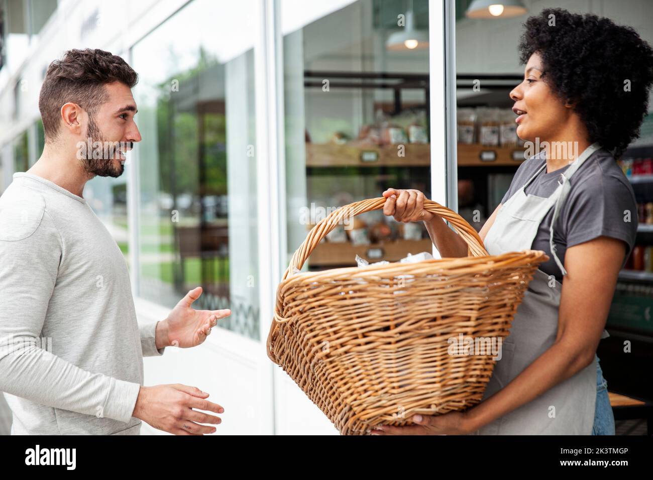 African American female bakery worker receiving basket from colleague Stock Photo
