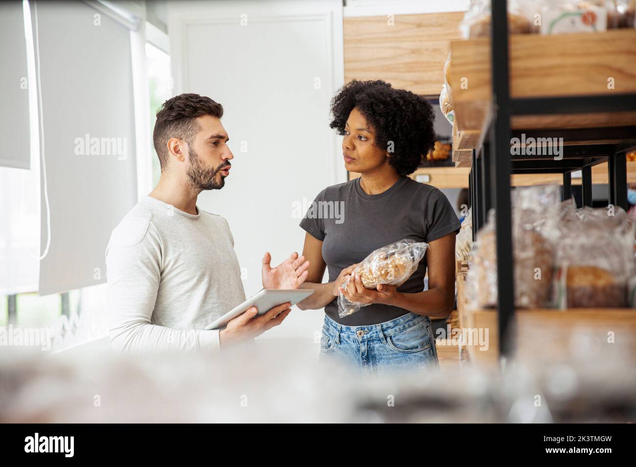 Male and female entrepreneur discussing while taking inventory Stock Photo