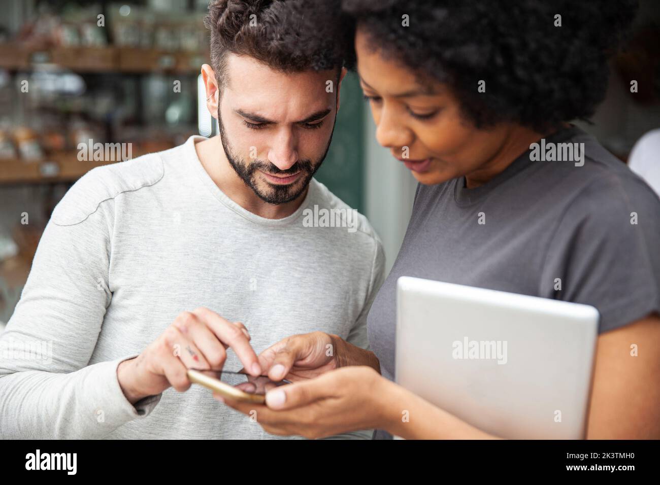 Bakery colleagues setting up social media on smart phone Stock Photo