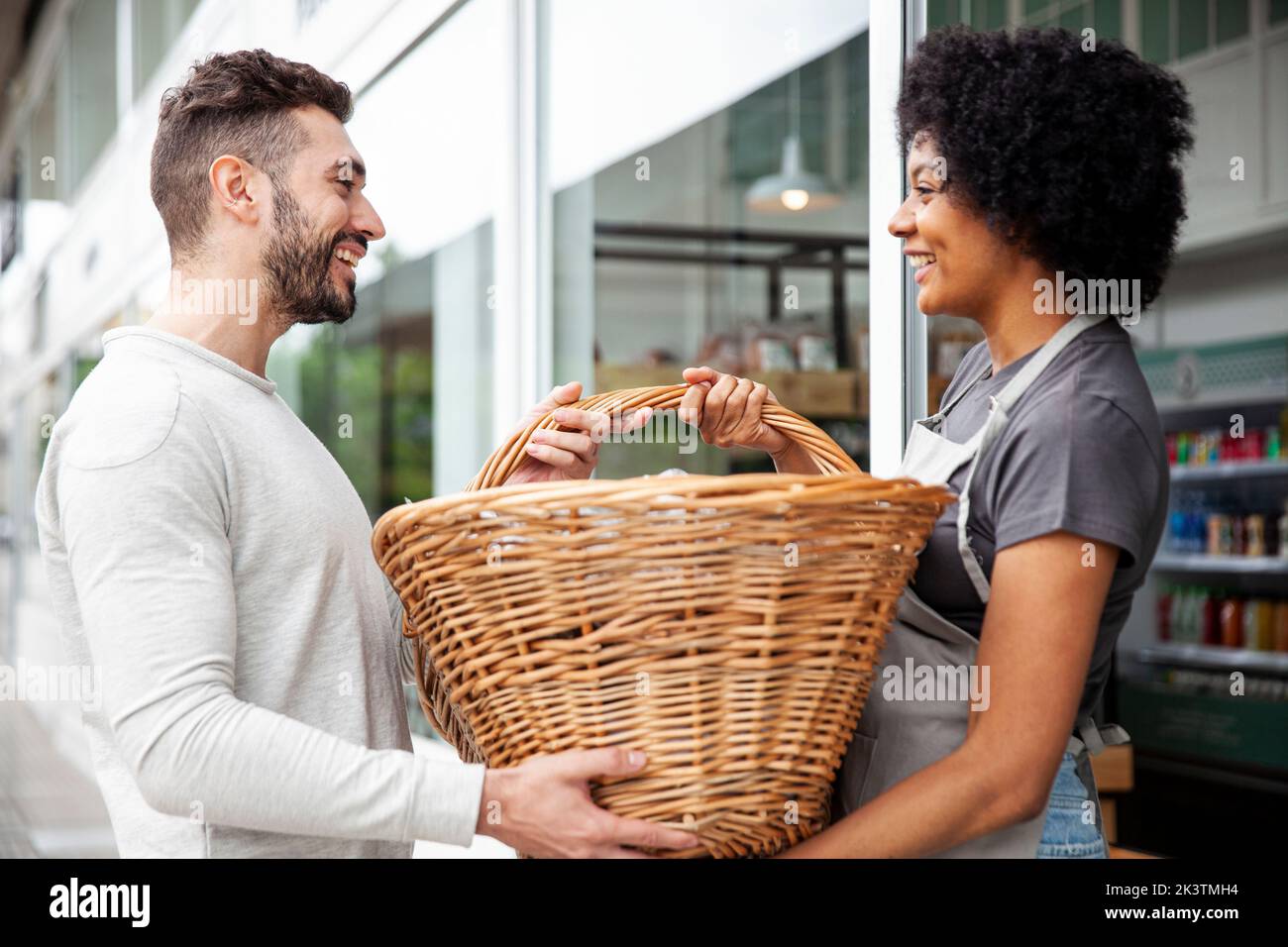 Male bakery worker delivering basket to colleague Stock Photo
