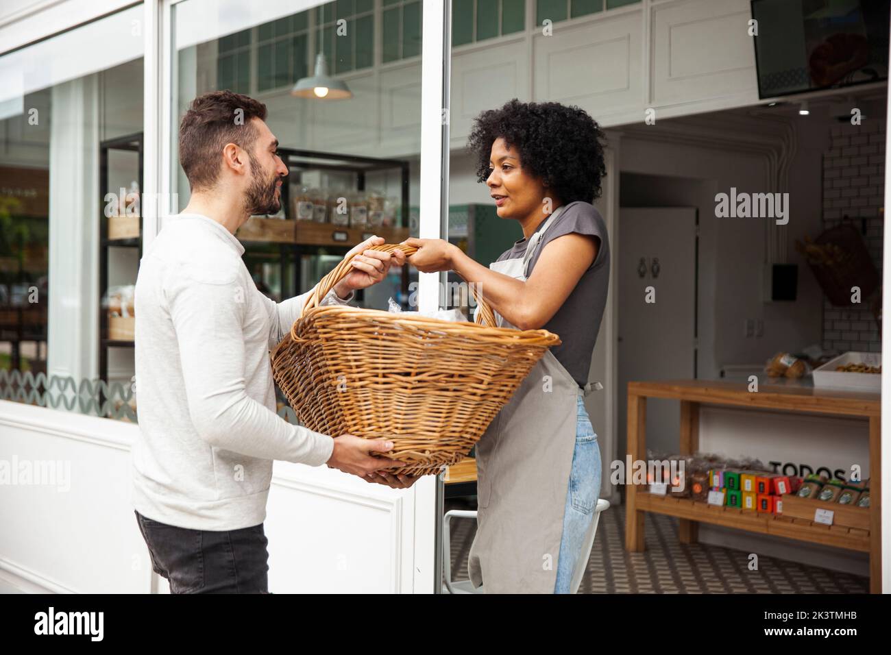 Bakery coworkers holding big basket while standing at doorway Stock Photo