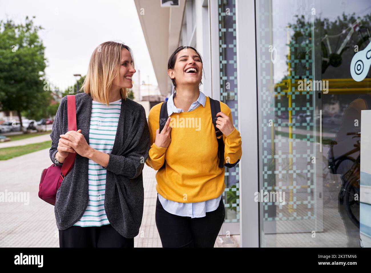 Mid-shot photo of two female friends having a good time outdoors while window shopping Stock Photo