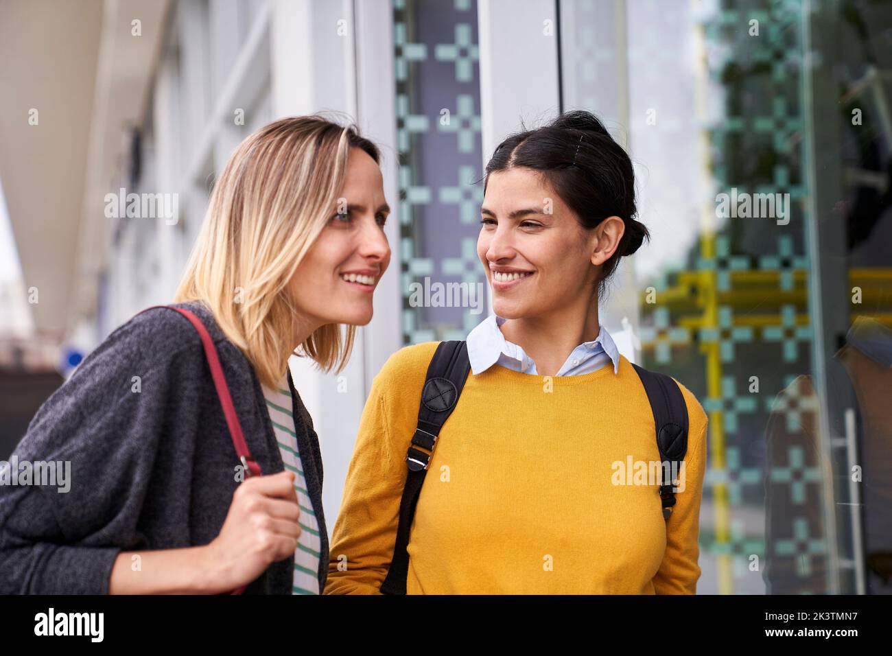 Mid-shot of two female friends taking a walk outdoors while window shopping Stock Photo