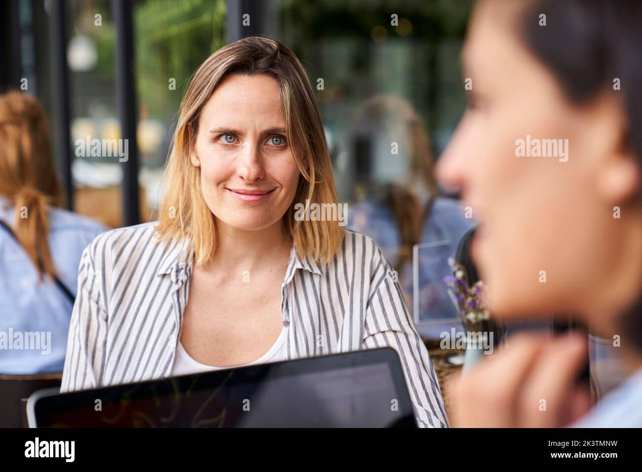 Front view of female entrepreneur working with her Latin-American partner seen out of focus from behind Stock Photo