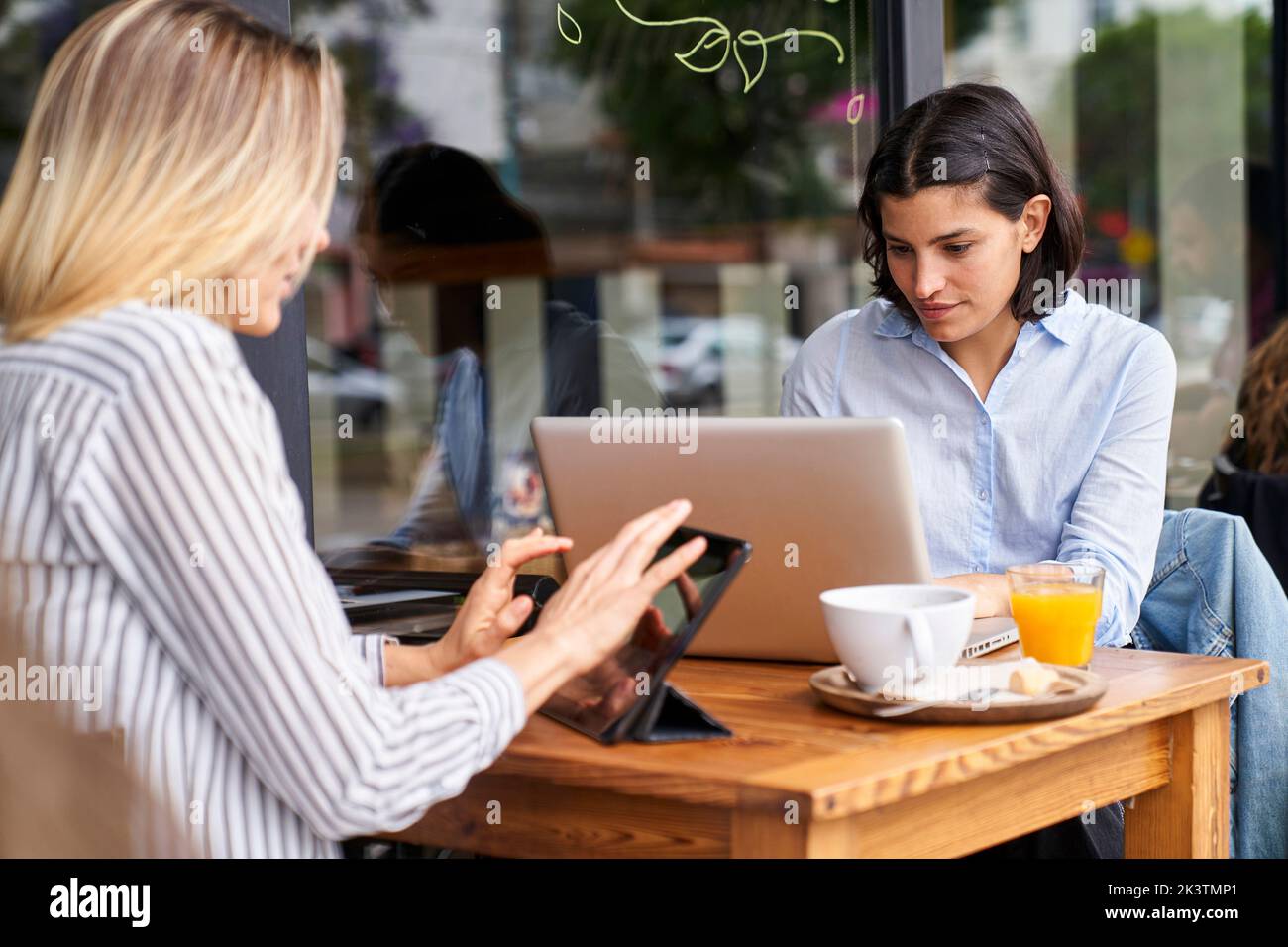 Medium-shot of two female diverse co-workers focused on their work in outdoors office Stock Photo