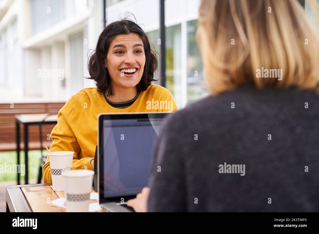 Mid-shot of two smiling female co-workers discussing business matters outdoors Stock Photo