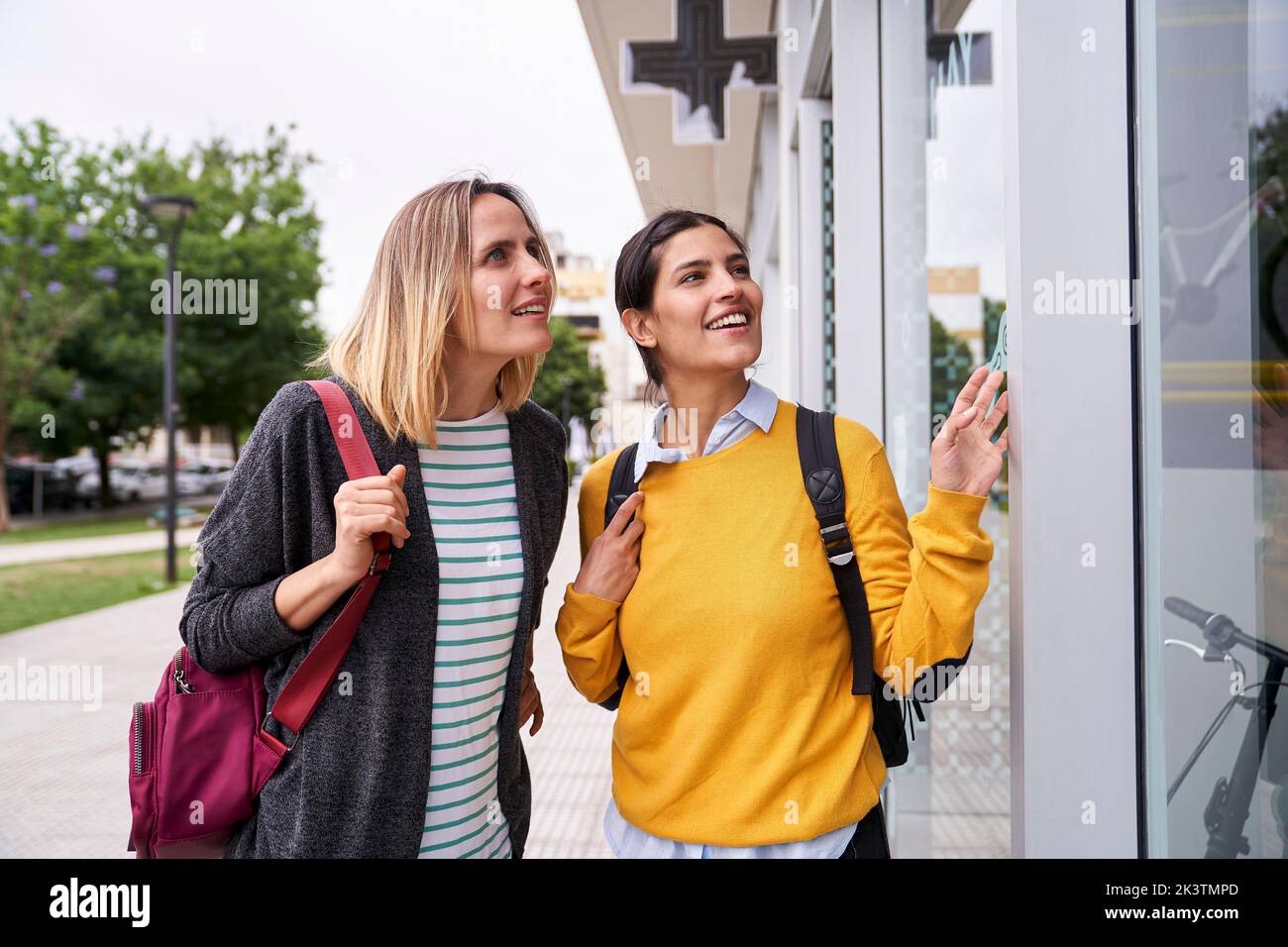 Photo of two female friends looking at shop windows and having a good time together Stock Photo