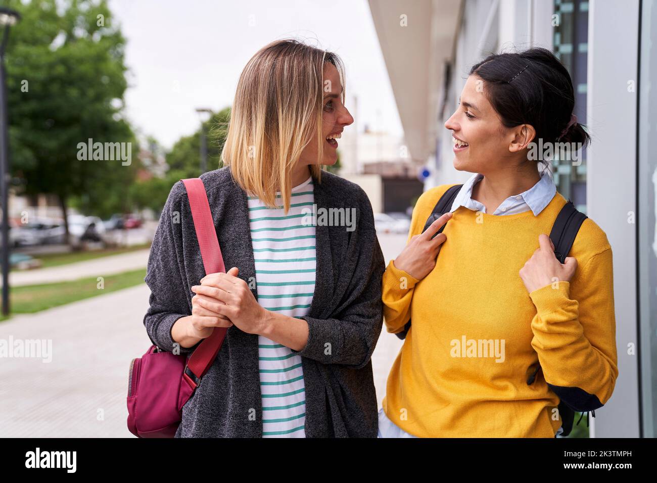 Medium shot of two female friends looking at each other while taking a walk outdoors Stock Photo