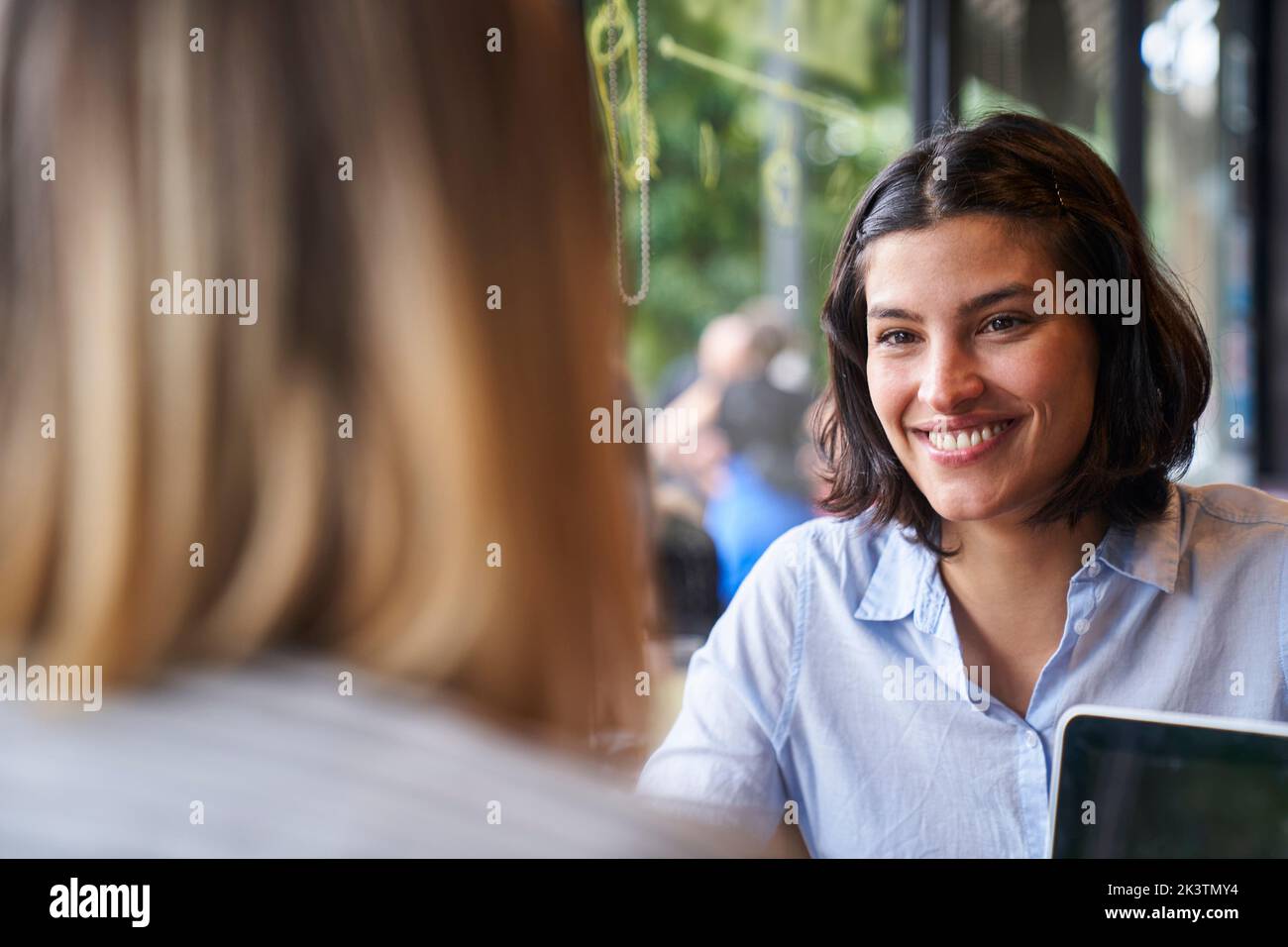 Medium front shot of Latin-American business woman and her colleague's back at company's cafeteria Stock Photo